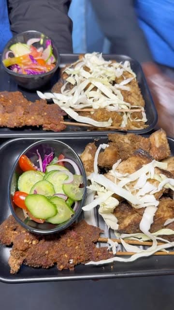 A spread of suya-spiced skewers, fried chops and coleslaw laid out for an event